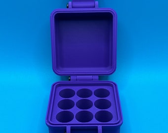 May include: A purple plastic storage case with a hinged lid, featuring an open interior compartment with a grid of nine circular holes arranged in a three-by-three pattern. The case includes a latch mechanism and a visible black metal hinge pin.
