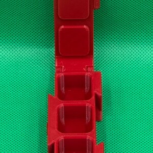 Puede incluir: Un recipiente de pl&aacute;stico rojo con cuatro compartimentos, cada uno con una tapa con bisagras. El recipiente est&aacute; dise&ntilde;ado para contener objetos peque&ntilde;os, como p&iacute;ldoras o joyas.