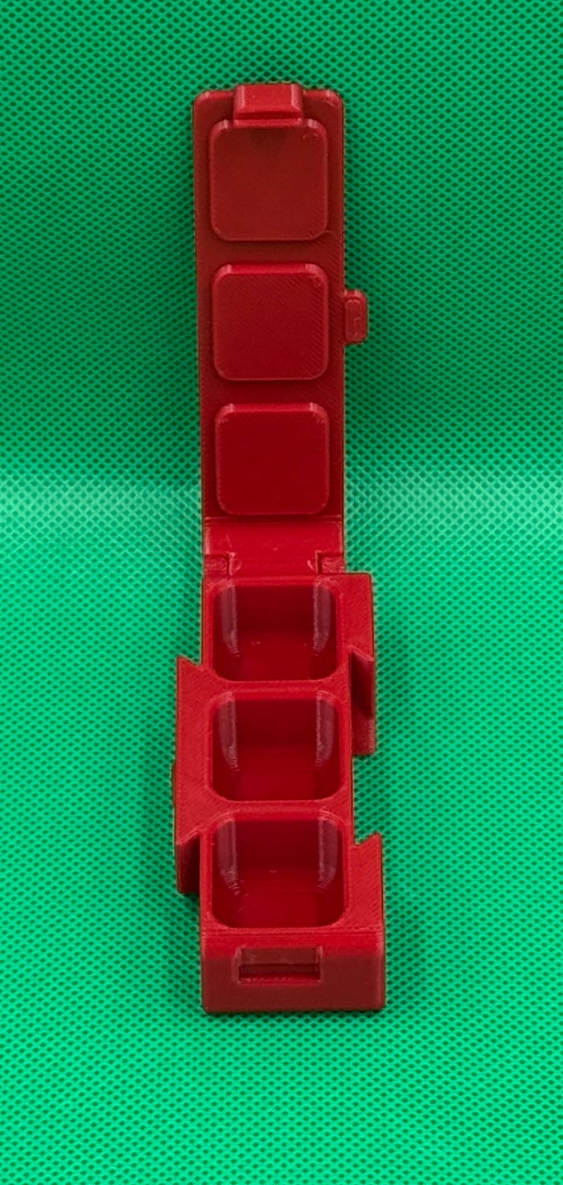 Puede incluir: Un recipiente de pl&aacute;stico rojo con cuatro compartimentos, cada uno con una tapa con bisagras. El recipiente est&aacute; dise&ntilde;ado para contener objetos peque&ntilde;os, como p&iacute;ldoras o joyas.