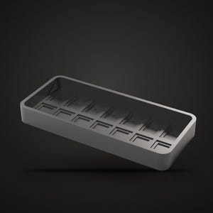 Könnte beinhalten: Ein rechteckiges, mattes dunkelgraues Gehäuse für eine mechanische Tastatur mit hohlem Innenraum, das eine Reihe quadratischer Aussparungen entlang der Basis für die Schaltermontage aufweist. Der Rahmen hat abgerundete Ecken.