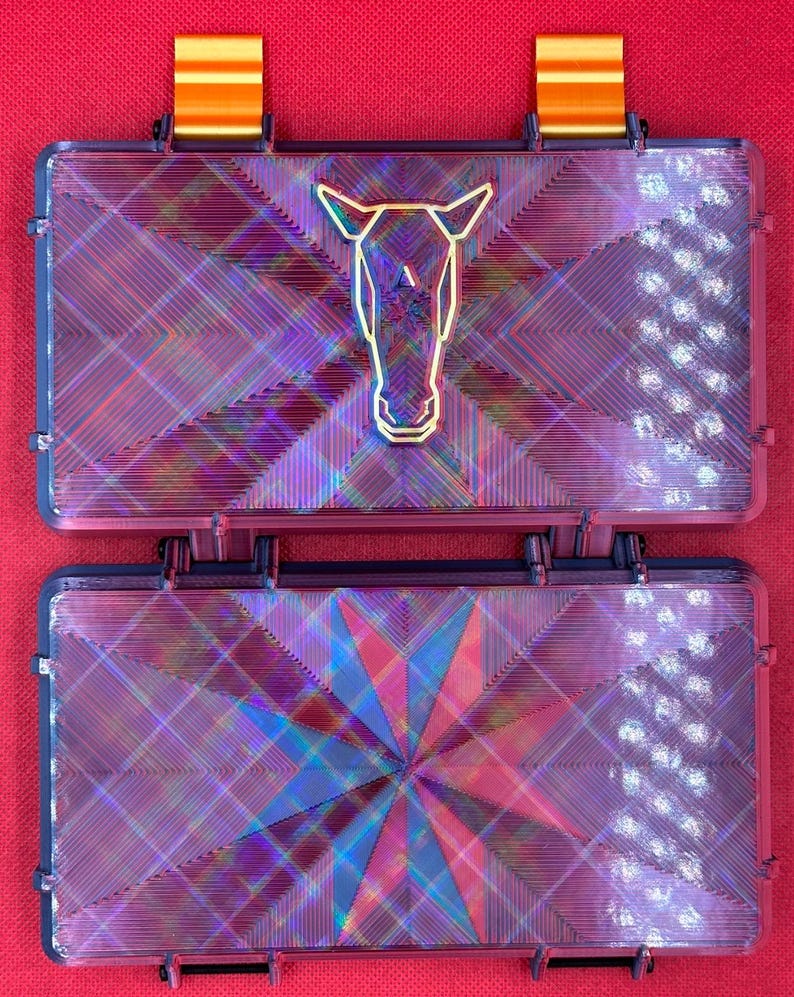 May include: Two iridescent purple and blue plastic boxes with a geometric pattern. The top box has a gold horse head design.