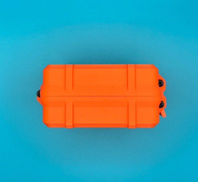 May include: A rectangular, bright orange protective storage case featuring a rigid, ribbed exterior design. The case is secured with small black screws visible along the side edge, presenting a durable, utilitarian construction.