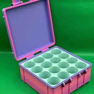 May include: A pink and purple hard plastic case with a light green foam insert. The case has 12 circular compartments.
