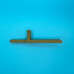 May include: A matte olive green plastic tool featuring a long, flat, horizontal bar with a perpendicular vertical tab extending from the center. The object has a smooth, uniform finish and a simple, functional, linear design structure.