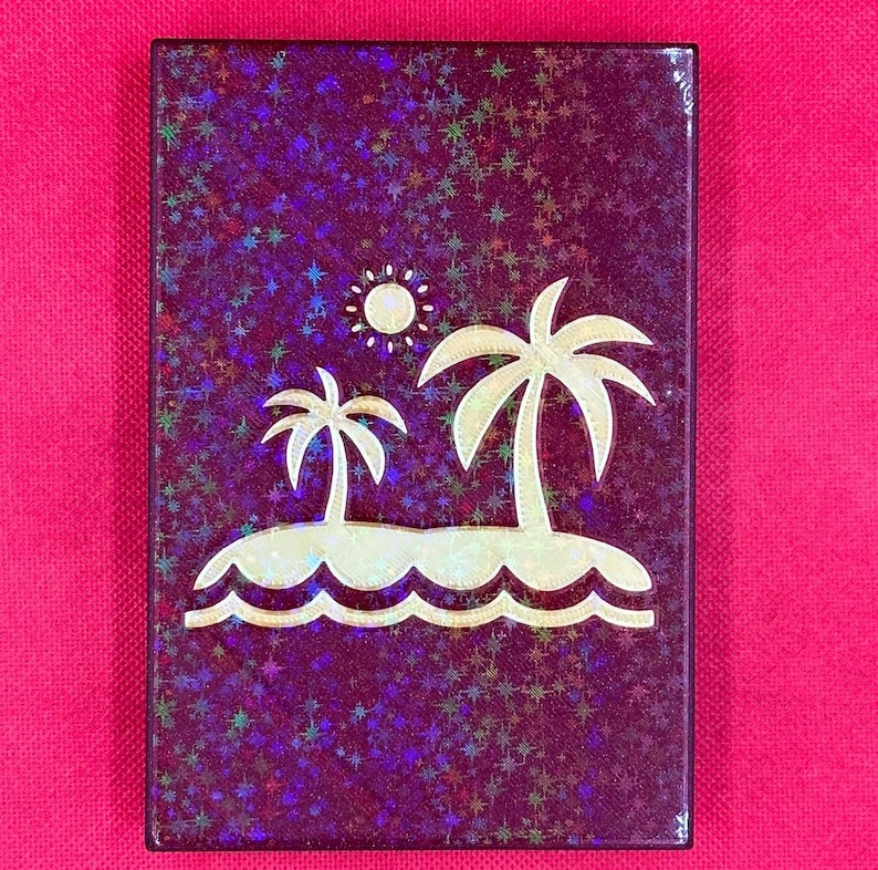 K&ouml;nnte beinhalten: Eine violette Karte mit einem goldenen Glitzerhintergrund und einem Design aus zwei Palmen auf einer Insel mit einer Sonne dar&uuml;ber.