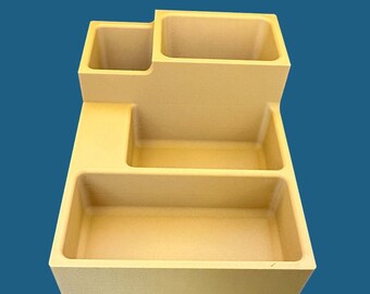 May include: A beige plastic organizer with four compartments. The organizer has a rectangular shape with a raised section in the back.