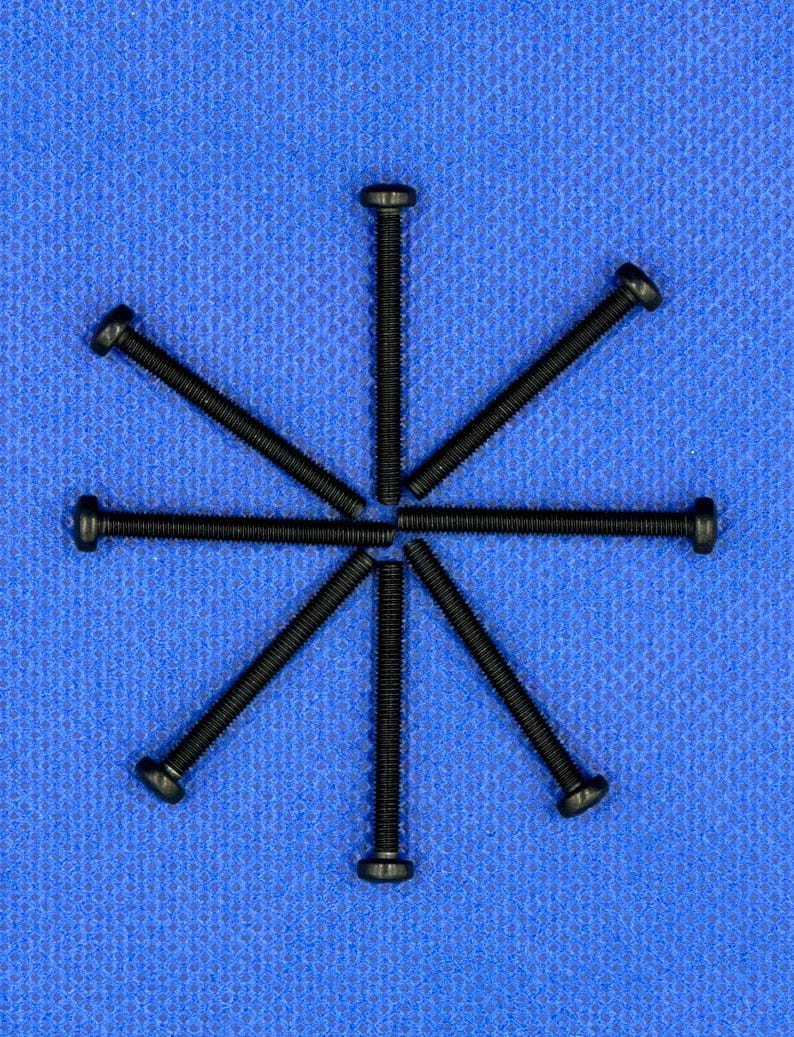 May include: Six black screws arranged in a star pattern on a blue surface.