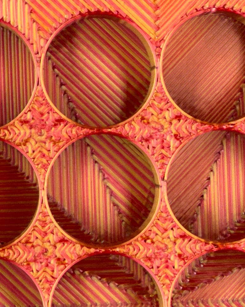 May include: A close-up of a woven basket with multiple circular openings. The basket is made of thin, red and yellow strips of material, creating a striped pattern.