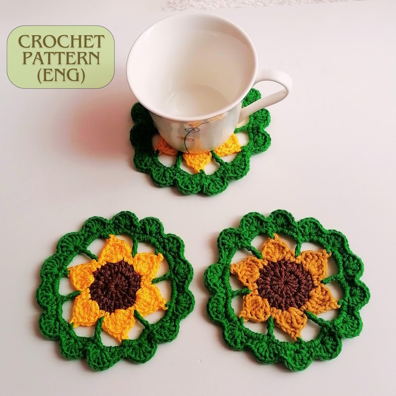 May include: Three crocheted sunflower coasters in green, yellow, and brown. The coasters are round and have a scalloped edge. A white ceramic mug is sitting on one of the coasters.