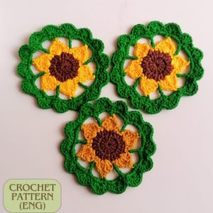 May include: Three crocheted sunflower motifs in shades of green, yellow, and brown. The sunflowers are made with a delicate stitch pattern and have a lacy appearance.