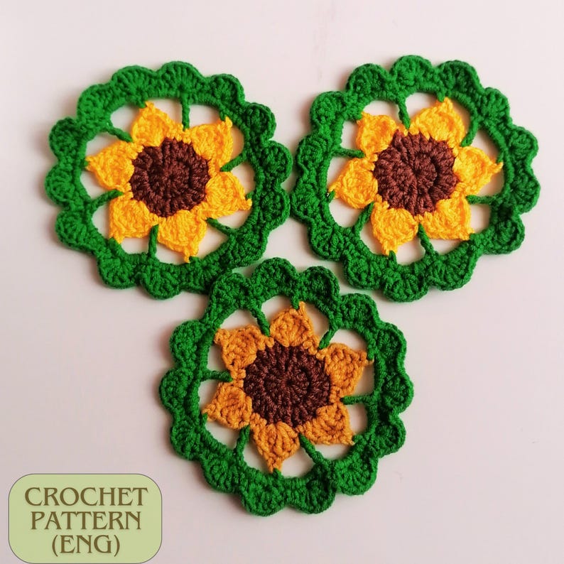 May include: Three crocheted sunflower motifs in shades of green, yellow, and brown. The sunflowers are made with a delicate stitch pattern and have a lacy appearance.