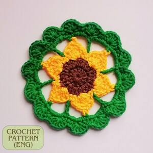 May include: A crocheted sunflower with a green outer ring and a yellow center with a brown center. The sunflower is a crochet pattern.