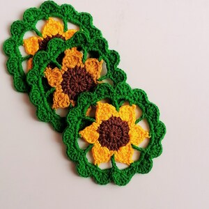 May include: Three crocheted sunflower coasters in green and yellow with brown centers.