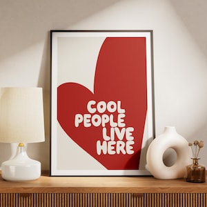 May include: A framed print featuring a red heart shape with the text "COOL PEOPLE LIVE HERE" in white lettering.