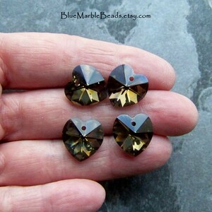 May include: Four brown crystal heart-shaped charms with a hole at the top for stringing. The charms are faceted and have a shiny finish.