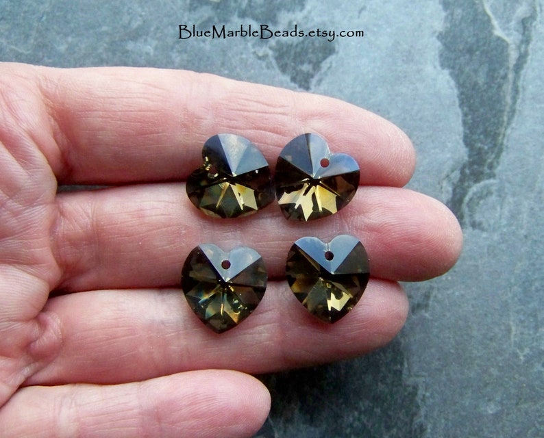 May include: Four brown crystal heart-shaped charms with a hole at the top for stringing. The charms are faceted and have a shiny finish.