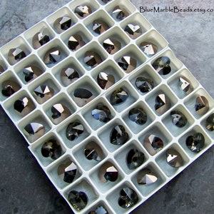 May include: A white plastic storage box filled with clear crystal heart-shaped beads. The beads are arranged in rows and columns, and they are all the same size. The box is labeled "BlueMarbleBeads.etsy.com".