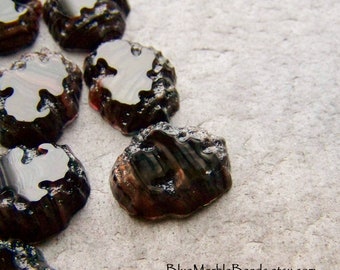 May include: A group of dark brown and black glass beads with a marbled effect. The beads are irregularly shaped and have a glossy finish.
