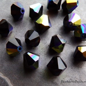 Puede incluir: Un conjunto de cuentas de cristal negro facetadas con cambios de color iridiscentes. Las cuentas tienen una forma geom&eacute;trica y un agujero para ensartar. La superficie refleja tonos de p&uacute;rpura, verde y dorado. Adecuado para la fabricaci&oacute;n de joyas.