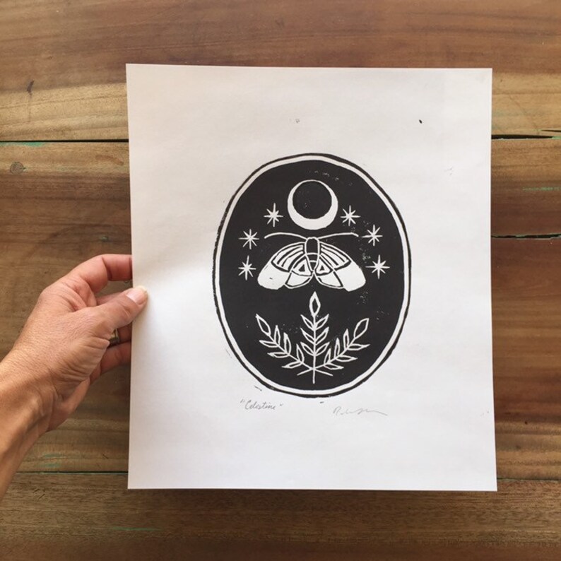 May include: Black and white print of a moth with wings spread, a crescent moon, and stars in a circle. The print is signed "Celestini" in the bottom right corner.