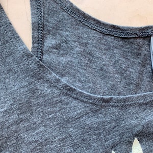 May include: A gray tank top with a white graphic print and a tag that reads "NEXT LEVEL" on the back.