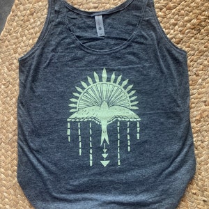 May include: A dark gray tank top with a light green graphic of a stylized bird with a sunburst design above it.