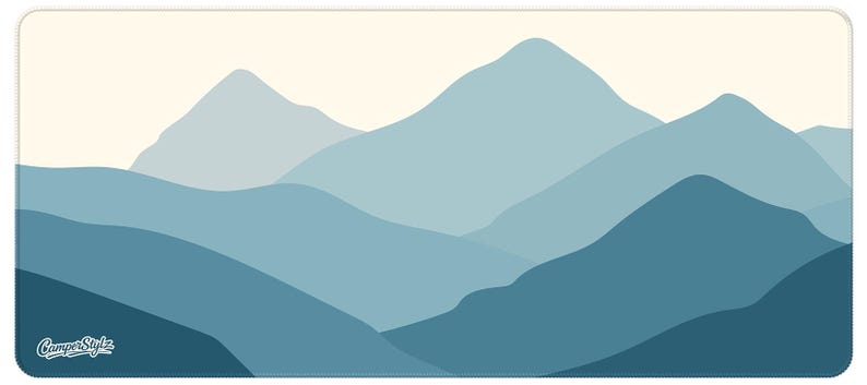 May include: A rectangular mat with a mountain range design in shades of blue and teal. The overlapping mountains create a layered effect against a cream sky. The text "Camper Style" is in the lower left corner.
