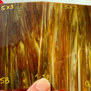 May include: Two sheets of 5x3 inch translucent brown and yellow marbled plastic with the text "5x3" and "SB" written on them.