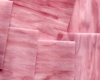 Puede incluir: Una colección de láminas de vidrio tintado rectangulares con una base rosa claro translúcida y vetas jaspeadas en rosa oscuro y blanco. Las piezas de vidrio están superpuestas, mostrando superficies lisas y opacidades variables en los tonos.