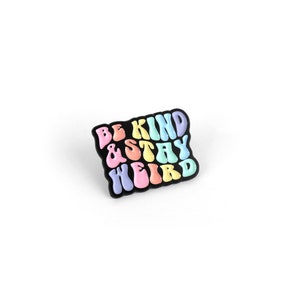 May include: A black enamel pin with the text "BE KIND & STAY WEIRD" in rainbow colors.