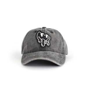 May include: A black denim baseball cap with a black and white dripping smiley face patch.