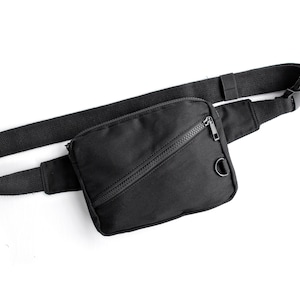 May include: A black fanny pack with a zipped pocket and a black adjustable strap.