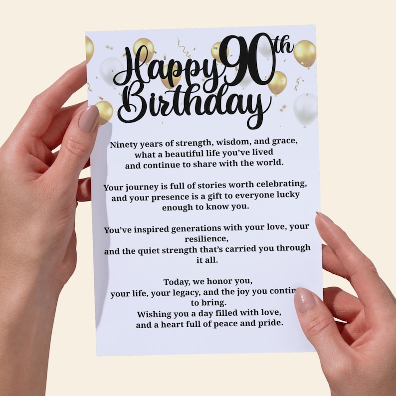 以下が含まれることがあります： 「Happy 90th Birthday」と黒い筆記体で書かれた白いグリーティングカード。カードは金と白の風船で飾られています。メッセージは、強さ、知恵、優雅さの人生を祝っています。
