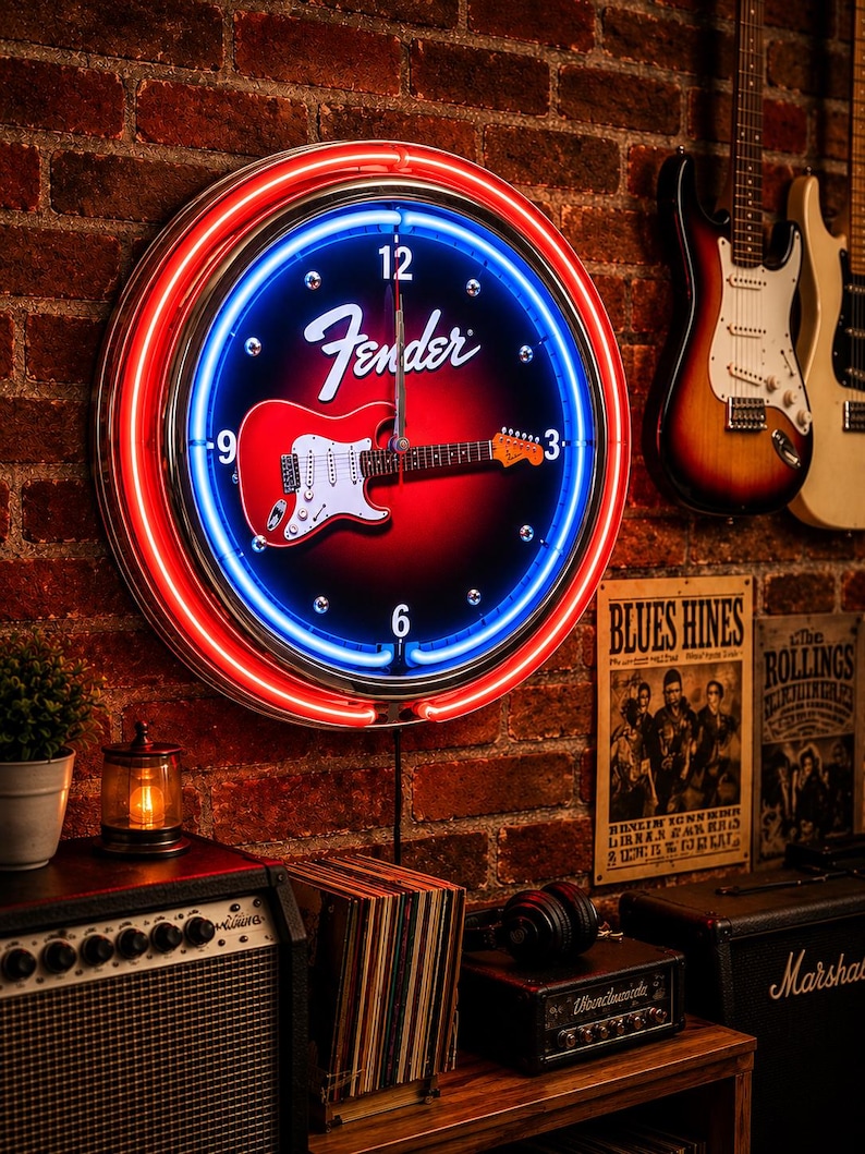 May include: A round Fender neon clock with a red and blue neon border. The clock face features a red guitar graphic and the Fender logo. The clock is mounted on a brick wall, with guitars visible in the background.