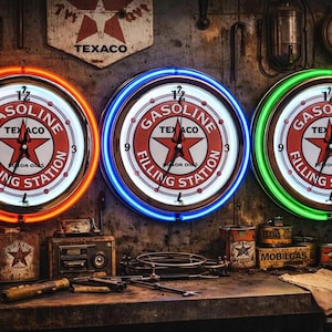 Op de afbeelding: Drie ronde wandklokken met het Texaco Gasoline Filling Station logo en een rode ster in het midden. Elke klok is omringd door een oplichtende neonring in respectievelijk oranje, blauw en groen, met zwarte wijzers en een witte wijzerplaat.
