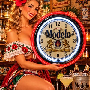 May include: A round Modelo neon wall clock with a red outer rim, black frame, and white face featuring the Modelo logo, numerals 1 through 12, and a central crest with two lions. The clock is illuminated by a bright white neon light ring.