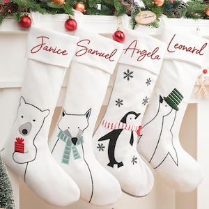 Può includere: Quattro calze di Natale bianche con nomi ricamati: Janice, Samuel, Angela e Leonard. Ogni calza presenta un diverso disegno di animali: un orso polare, una volpe, un pinguino e una creatura simile a un pinguino. Decorazioni festive.