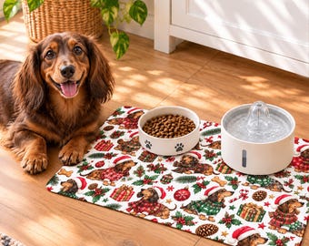 Può includere: Un tappetino rettangolare per animali domestici con un motivo ripetuto di bassotti che indossano maglioni natalizi e cappelli di Babbo Natale, intervallati da regali, rami di pino e ornamenti. Una ciotola in ceramica con croccantini e una fontanella d'acqua bianca sono posizionate sopra.