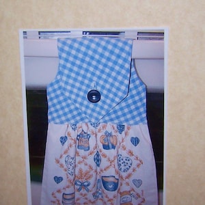 May include: A blue and white checkered stove towel with a floral design and the text "Little Craft Cottage".