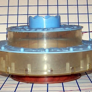 May include: A three-tiered, clear plastic rotating carousel with a light blue top and a brown base. The carousel is decorated with a light blue rim and small blue dots.
