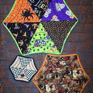 Könnte beinhalten: Drei gequiltete Tischsets zum Thema Halloween. Eines ist sternförmig mit einem Spinnennetz-Design und den Worten "Trick or Treat" in der Mitte. Ein anderes ist ein Spinnennetz-Design mit einer schwarzen Spinne in der Mitte. Das dritte ist ein Spinnennetz-Design mit verschiedenen Halloween-Motiven.