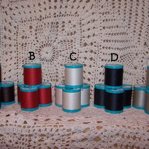May include: Five spools of thread in different colors, arranged in a row. The spools are labeled A through E. The colors are brown, red, white, black, and gray.