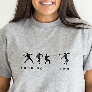 May include: A light gray t-shirt featuring a black graphic of track and field athletes in action. The text "running...ewe" is printed below the athletes. The shirt has short sleeves and a crew neck.