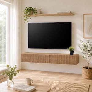Peut inclure: Une console multimédia flottante fixée au mur avec une finition en bois clair et des lattes verticales. Au-dessus de la console, un téléviseur à écran plat est fixé au mur, avec une étagère en bois contenant une petite plante et des livres.