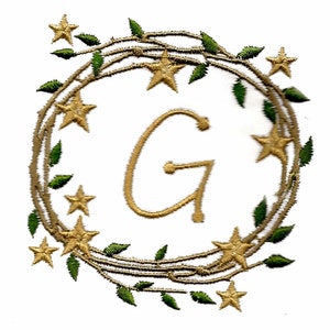 May include: A gold letter G surrounded by a wreath of gold vines and green leaves with gold stars.