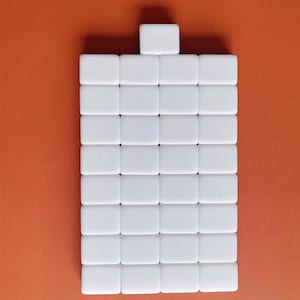 May include: A white rectangular tile set with 36 individual tiles arranged in a grid pattern. The tiles are all the same size and shape, and they are arranged in a neat and orderly fashion.