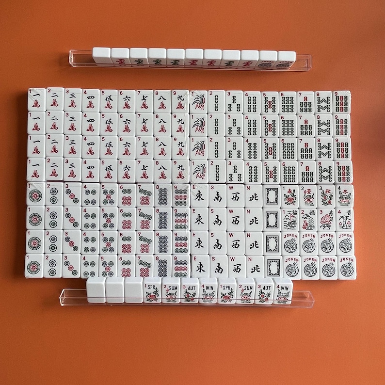 May include: A set of white dominoes with black dots and red numbers. The dominoes are arranged in a rectangular grid with a row of dominoes at the top and bottom. The dominoes are numbered 1 through 9 and have the suits of bamboo, circle, character, and wind.