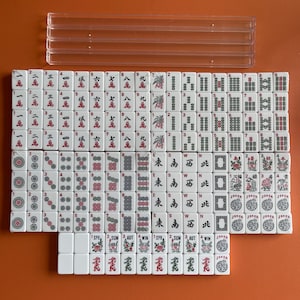 May include: A set of white mahjong tiles with red and black markings. The tiles are arranged in rows and columns, with the numbers 1 through 9, the characters East, South, West, North, and the words 'Joker' and 'Win'.