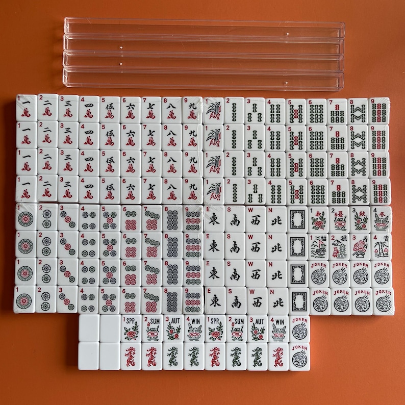 May include: A set of white mahjong tiles with red and black markings. The tiles are arranged in rows and columns, with the numbers 1 through 9, the characters East, South, West, North, and the words 'Joker' and 'Win'.