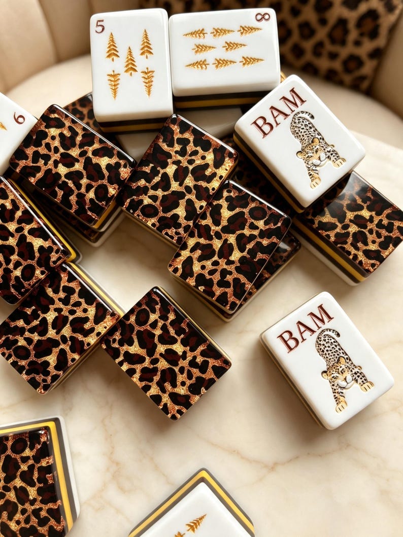 May include: A collection of rectangular mahjong tiles featuring a mix of designs. Some tiles display a brown and black leopard print pattern, while others are white with gold tree illustrations or a leopard graphic with the text BAM.